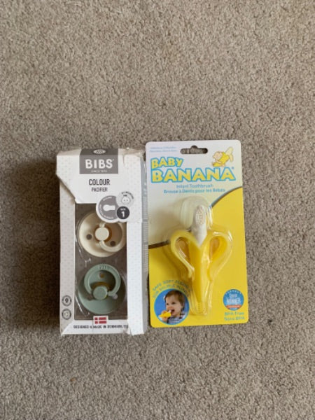 2 bins pacifiers and a banana toothbrush